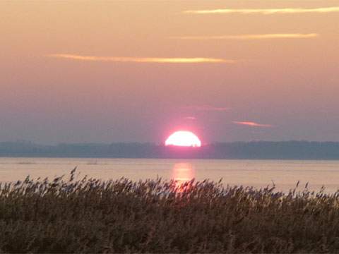 Sonnenuntergang über der Eisfläche des Achterwassers: Winterurlaub auf der Insel Usedom.