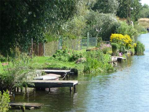 An der Peene: Liebevoll gestaltete kleine Laubengärtchen am Peeneufer.